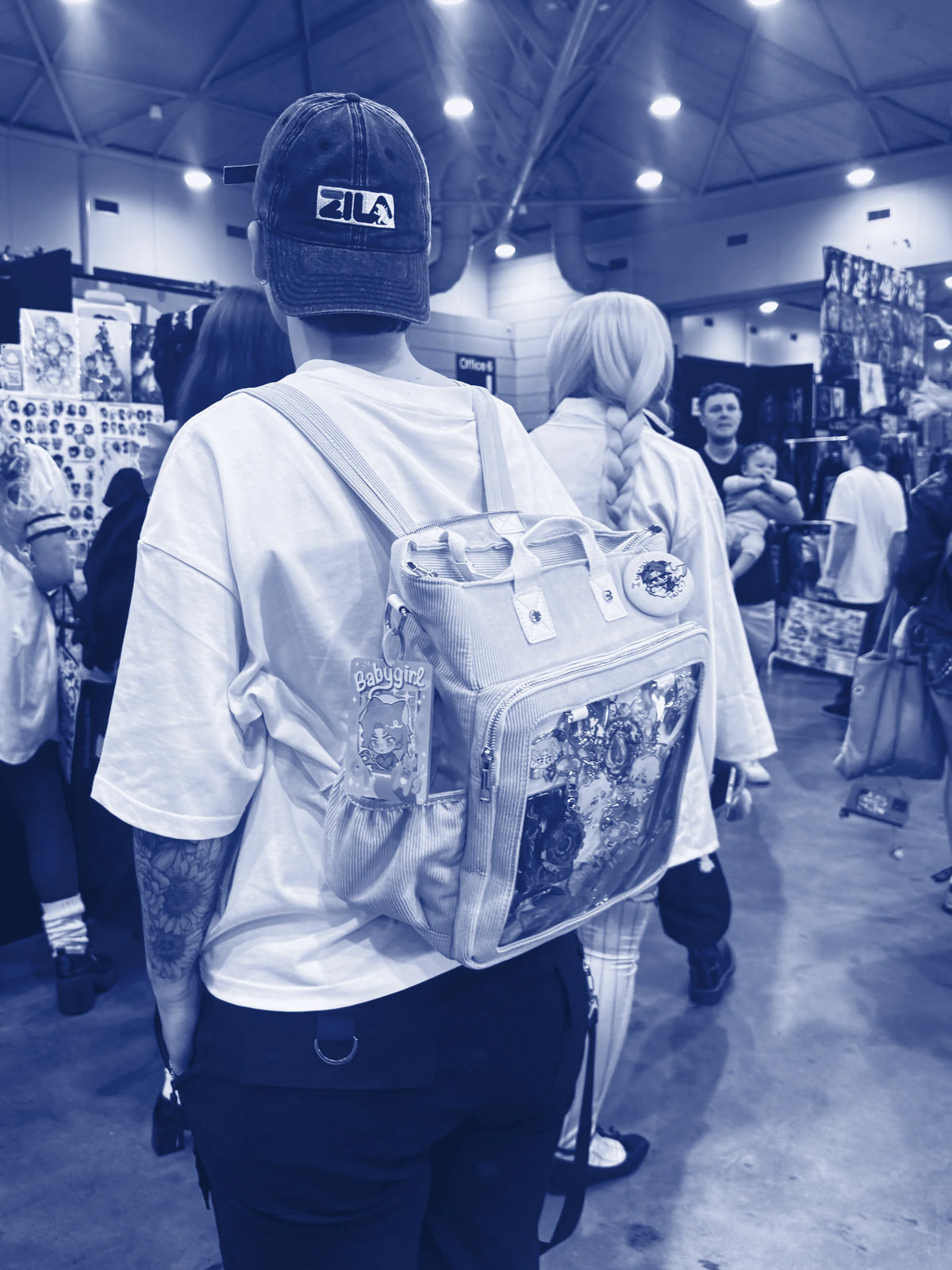 Someone wearing a pin-filled ITA backpack at a convention
