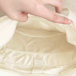 Hand opening the zip top of the beige 16" ITA laptop tote